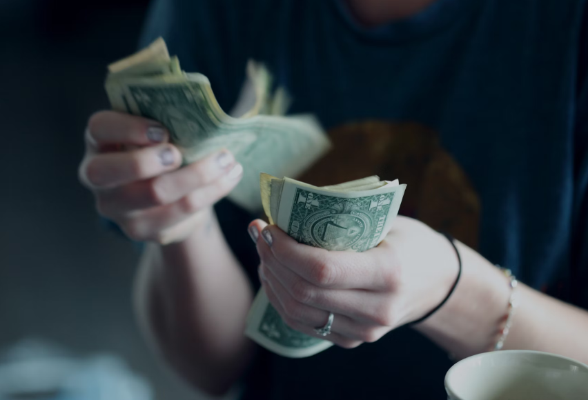 Person counting a stack of U.S. dollar bills 